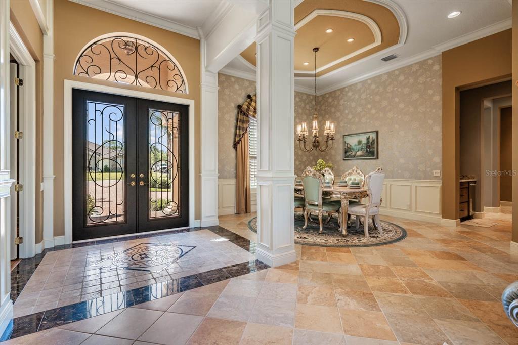 An entryway with tile flooring and a double front door leads to a formal dining room — 13327 CARNOUSTIE CIRCLE, DADE CITY, FL