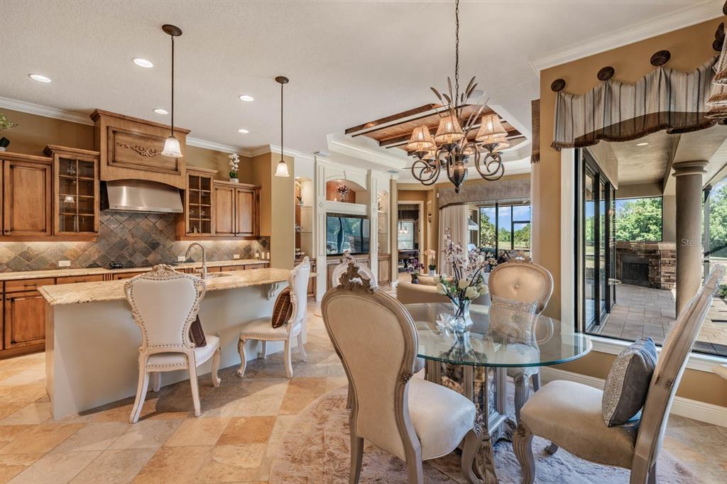 A kitchen and dining area with wood cabinets, granite countertops, and a glass-topped table — 13327 CARNOUSTIE CIRCLE, DADE CITY, FL