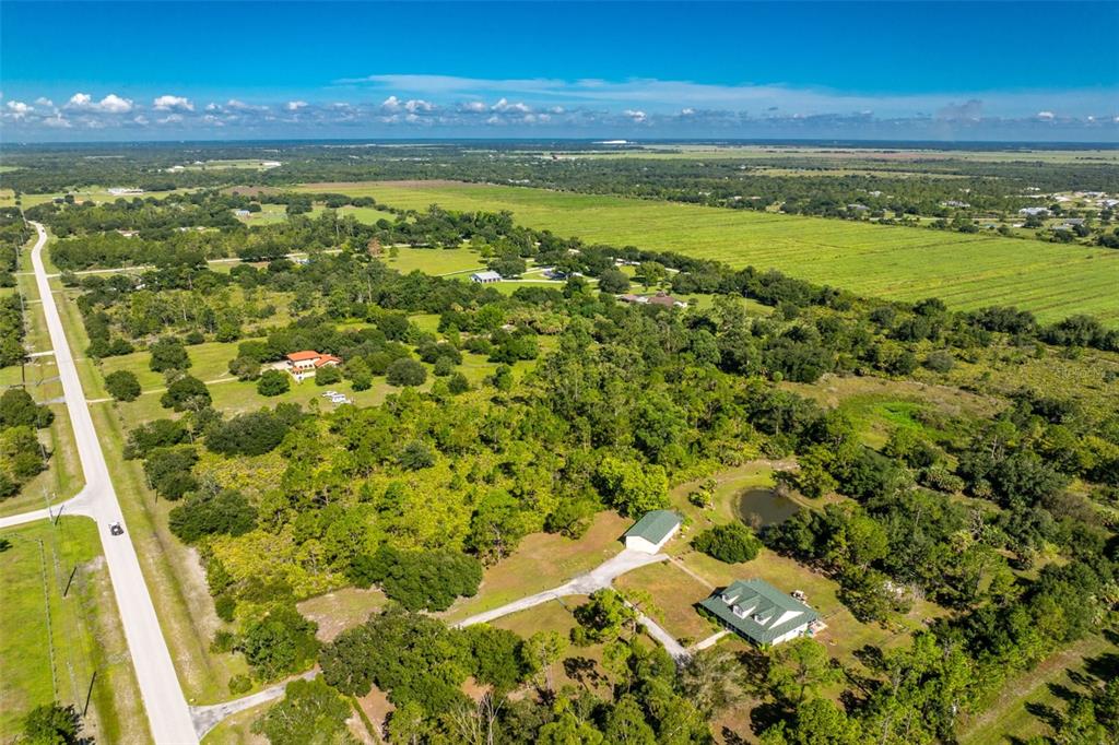 An aerial view shows a rural property with two houses, a shed, and a pond — 16550 PRAIRIE CREEK BOULEVARD, PUNTA GORDA, FL