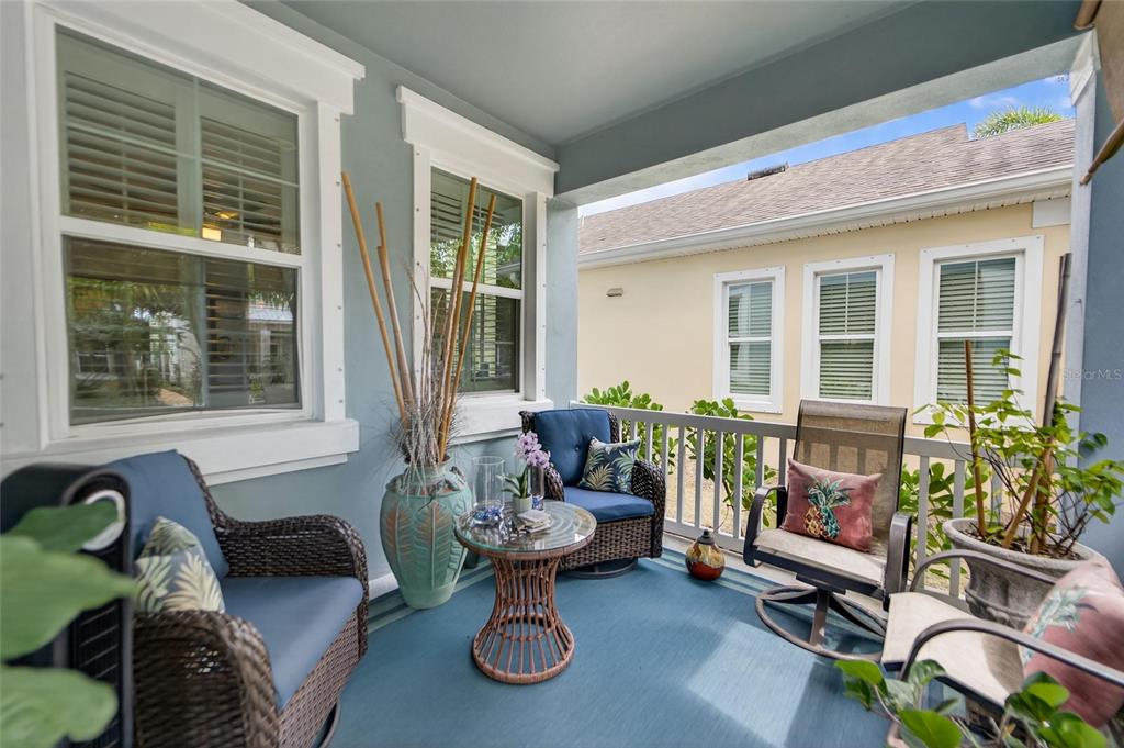 A covered porch features wicker furniture, a small glass-topped table, and blue outdoor carpeting — 623 WINTERSIDE DRIVE, APOLLO BEACH, FL