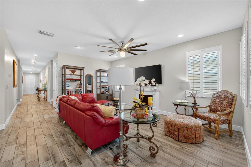 A living room features a red leather sofa, a fireplace, and wood-look tile flooring — 623 WINTERSIDE DRIVE, APOLLO BEACH, FL