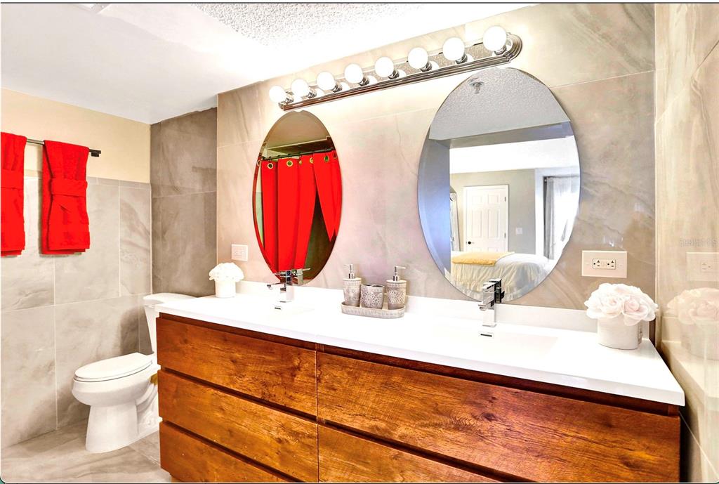 A bathroom features a double vanity with a wood cabinet, white countertop, and two oval mirrors — 3940 INVERRARY BOULEVARD UNIT 703A, LAUDERHILL, FL