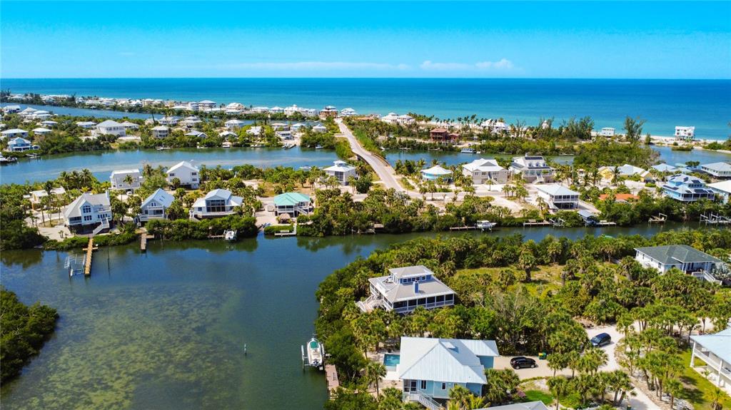 Aerial view of waterfront houses surrounded by lush vegetation and a canal near the ocean — 39 BAYSHORE CIRCLE, PLACIDA, FL