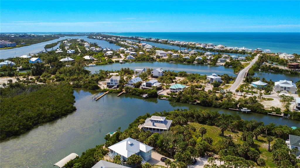 An aerial view shows waterfront houses surrounded by lush vegetation and canals near the ocean — 39 BAYSHORE CIRCLE, PLACIDA, FL