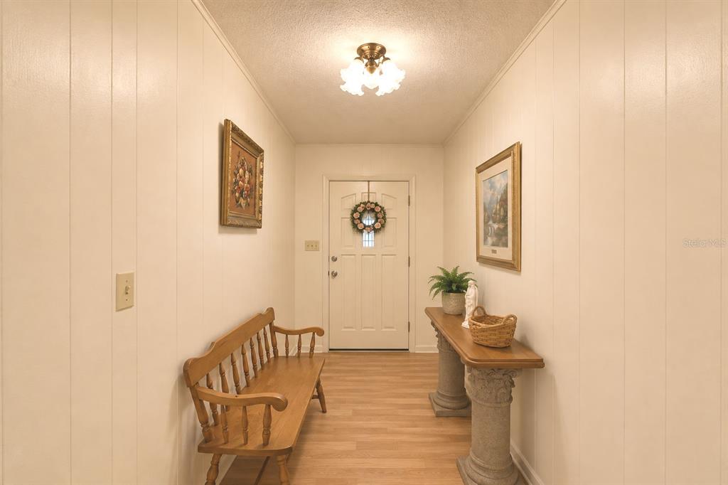 A foyer with wood-look flooring, a wooden bench, a console table, and a front door — 214 N LAKE REEDY BOULEVARD, FROSTPROOF, FL