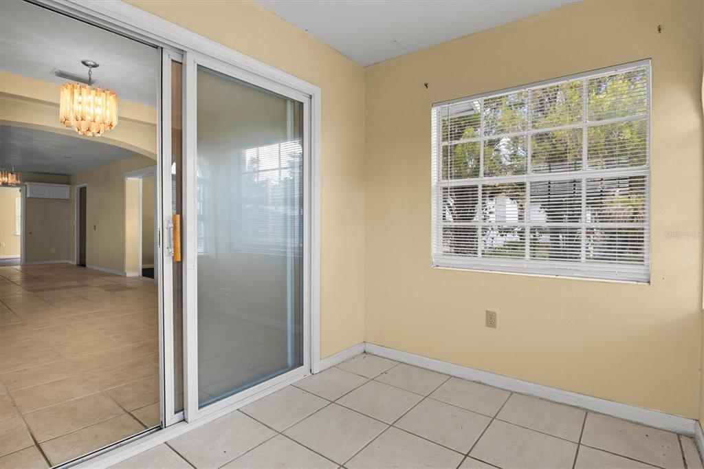 A sunroom with beige walls, tile flooring, a sliding glass door, and a window — 844 CHAMBERLAIN BOULEVARD, WAUCHULA, FL