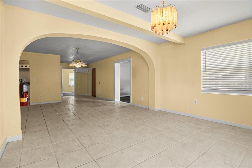 A spacious room with yellow walls, tiled floors, and an arched entryway leading to another room — 844 CHAMBERLAIN BOULEVARD, WAUCHULA, FL