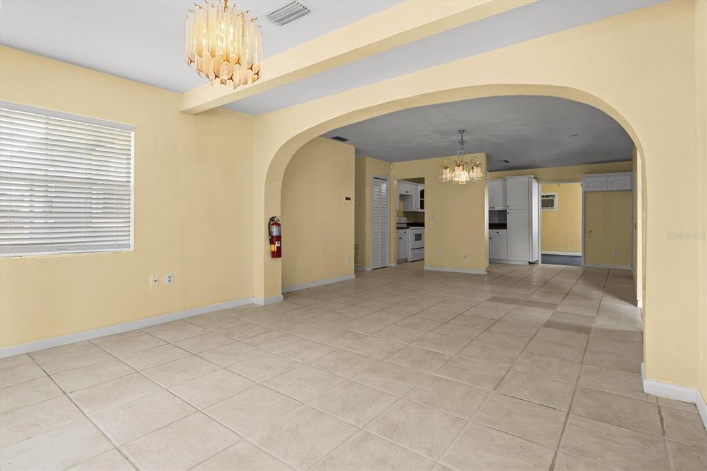 An open-concept living and dining area features yellow walls, tile flooring, and arched transitions — 844 CHAMBERLAIN BOULEVARD, WAUCHULA, FL