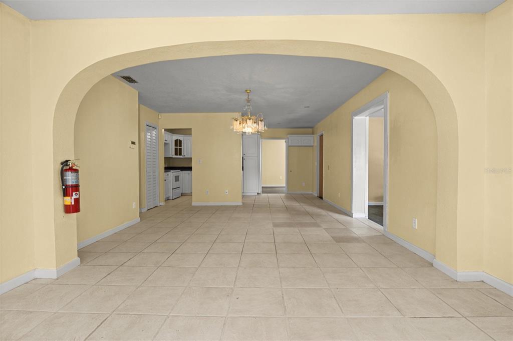 An interior view shows a tiled room with yellow walls, an arched opening, and a chandelier — 844 CHAMBERLAIN BOULEVARD, WAUCHULA, FL