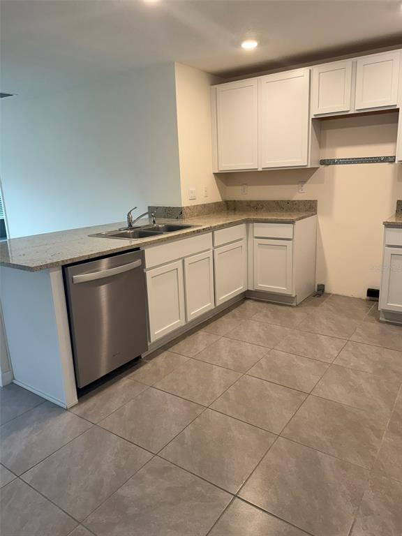 A kitchen features white cabinets, granite countertops, a stainless steel dishwasher, and light tile flooring — 1663 HAZY SEA DRIVE, PLANT CITY, FL