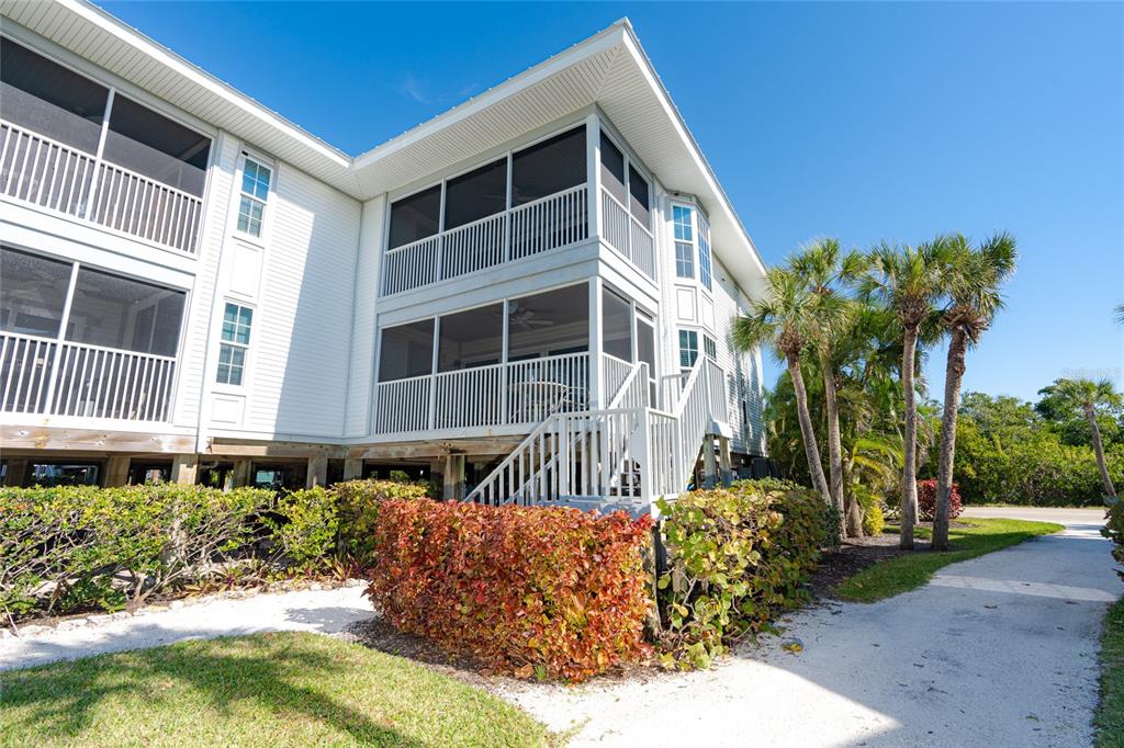 An exterior view of a two-story elevated building with screened-in porches and a staircase — 7450 PALM ISLAND DRIVE UNIT 3411, PLACIDA, FL