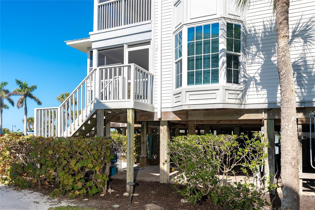 An elevated white house features a screened porch with stairs and a bay window — 7450 PALM ISLAND DRIVE UNIT 3411, PLACIDA, FL