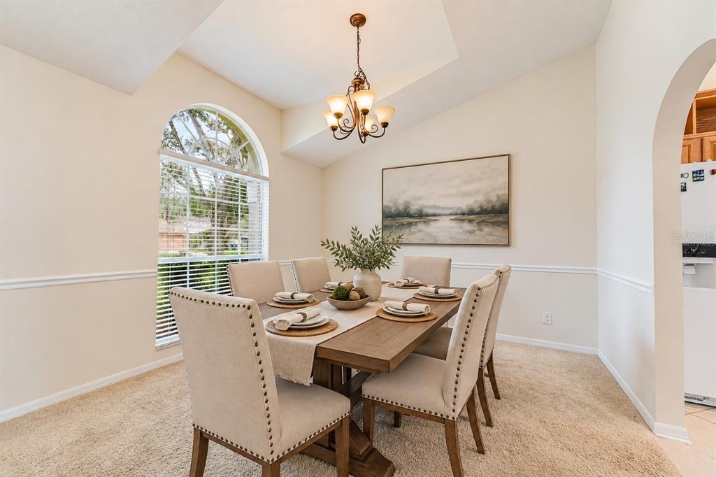 A dining room features a wooden table, upholstered chairs, a chandelier, and a large window — 349 BENTLEY STREET, OVIEDO, FL