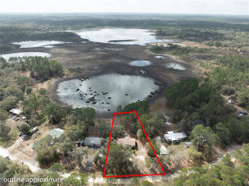 An aerial view shows a house on a lot outlined in red near a lake — 5711 CARIBBEAN CIRCLE, KEYSTONE HEIGHTS, FL