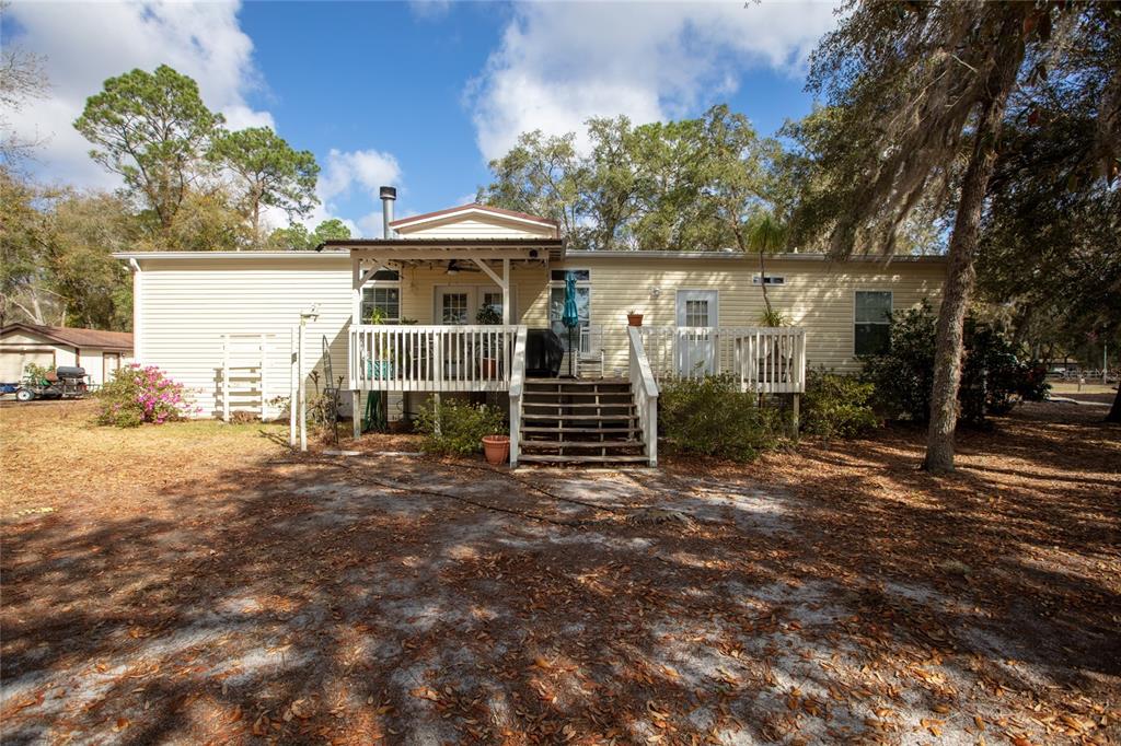 A single-story house with light yellow siding features a raised wooden deck and stairs — 5711 CARIBBEAN CIRCLE, KEYSTONE HEIGHTS, FL