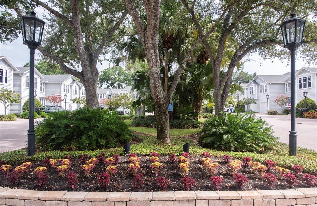 A landscaped garden bed with colorful plants sits in front of multi-story residential buildings — 2311 W MORRISON AVENUE UNIT 26, TAMPA, FL