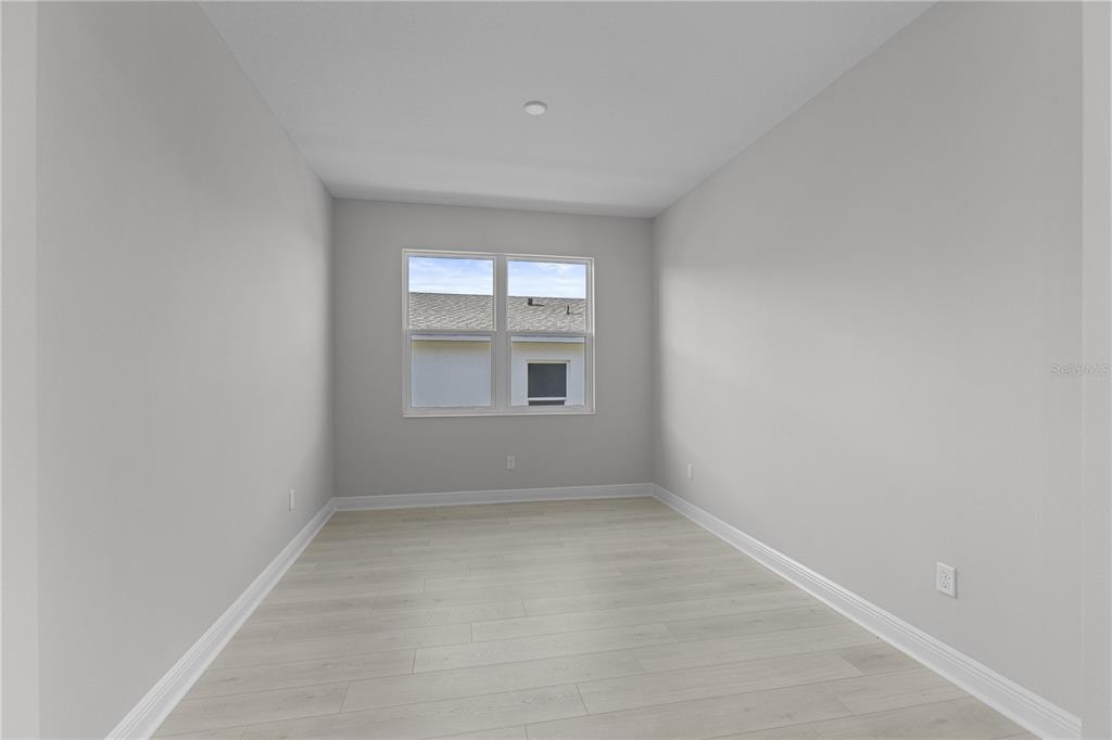 An empty room with light gray walls, white trim, and light wood-look flooring — 1727 POINT GRACE ROAD, TAVARES, FL