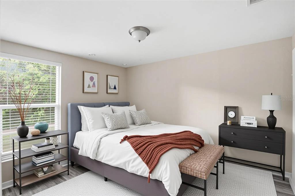 A bedroom with a gray bed, a black dresser, a bookshelf, and a window — 1514 CREST AVENUE, LEESBURG, FL