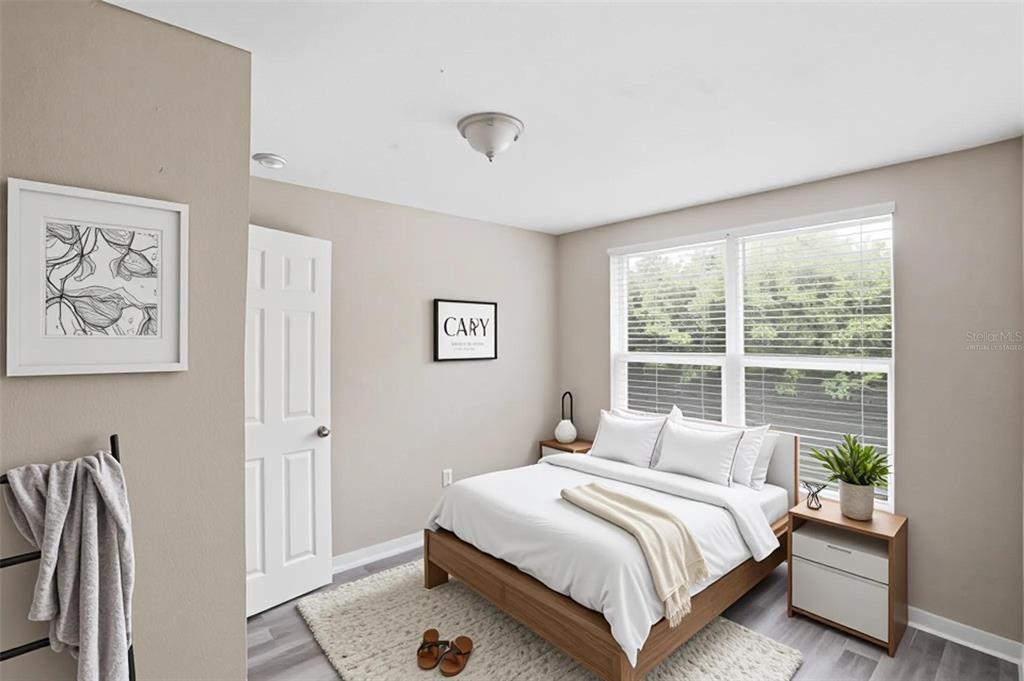 A bedroom with light walls, a wooden bed frame, a white rug, and a window — 1514 CREST AVENUE, LEESBURG, FL