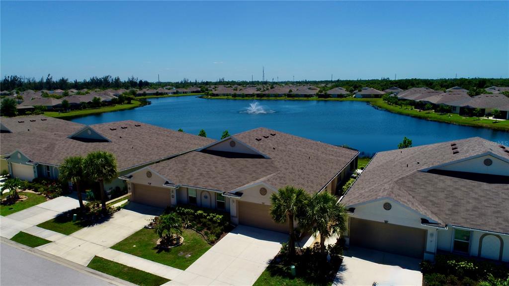 An aerial view of suburban houses with brown roofs situated around a central lake — 25161 E LENOX CIRCLE, PUNTA GORDA, FL