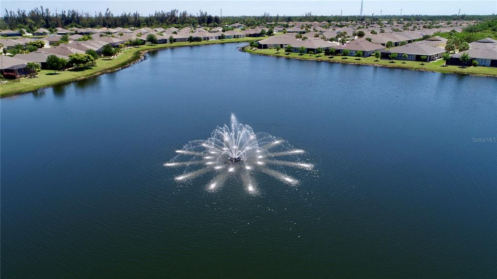 An aerial view of a large pond with a fountain surrounded by suburban houses — 25161 E LENOX CIRCLE, PUNTA GORDA, FL