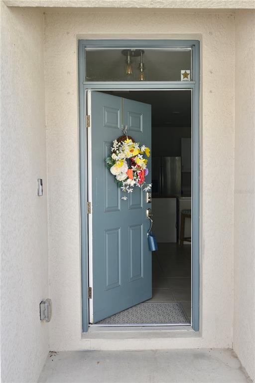 A blue front door with a floral wreath stands open to a home interior — 25161 E LENOX CIRCLE, PUNTA GORDA, FL