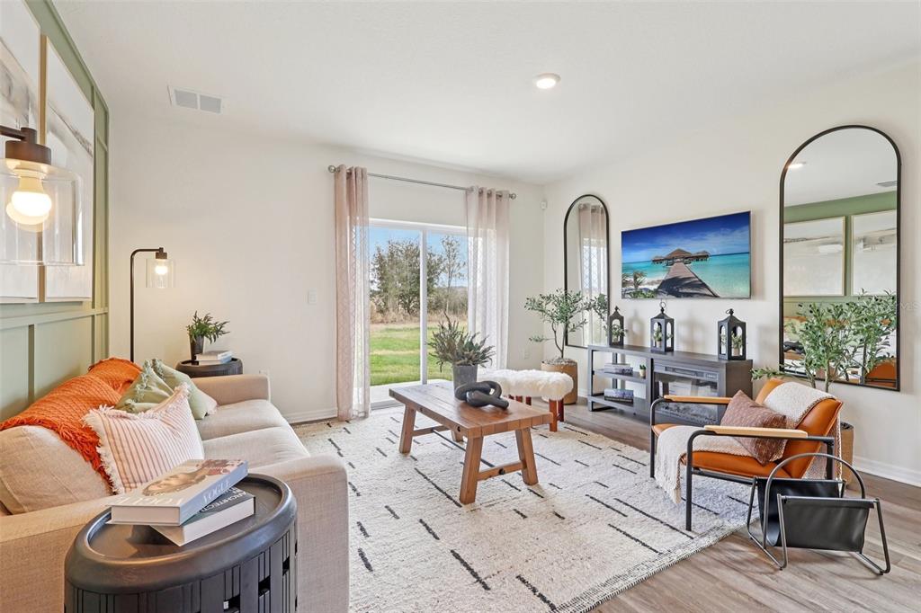 A living room features a beige sofa, wooden coffee table, armchair, and a wall-mounted television — 4003 LIMEKLIN FALLS LOOP, DAVENPORT, FL