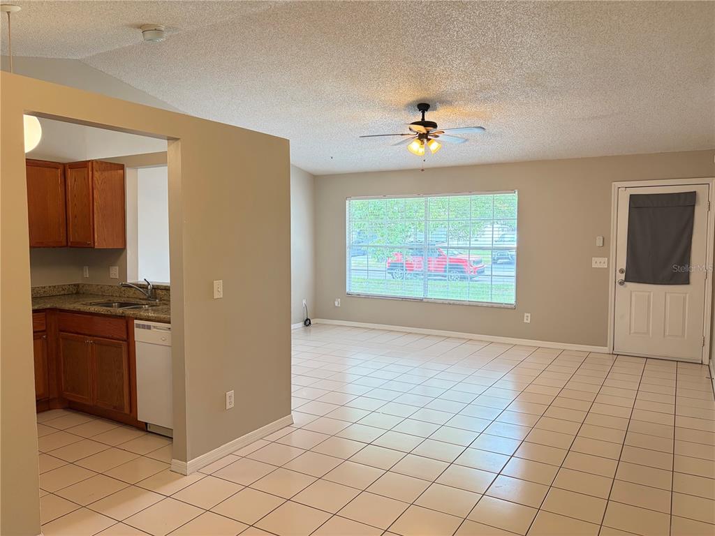 A kitchen with wood cabinets opens into a living area with tile floors and windows — 1224 ROMA COURT, ORLANDO, FL