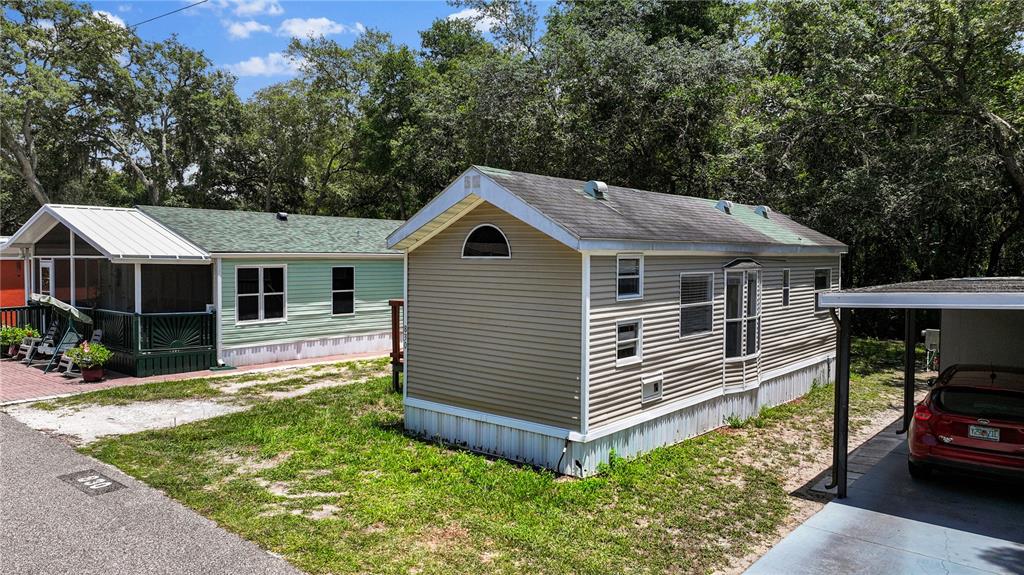 Two manufactured homes sit side-by-side on a grassy lot with a carport and trees — 3000 CLARCONA ROAD UNIT 830, APOPKA, FL