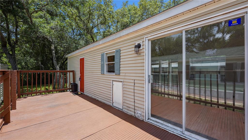 A wooden deck extends from the side of a house with beige siding and sliding doors — 3000 CLARCONA ROAD UNIT 830, APOPKA, FL
