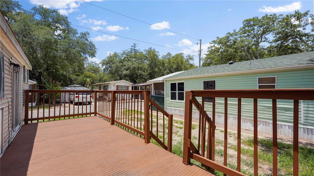 A wooden deck with railings overlooks a yard between two mobile homes under a blue sky — 3000 CLARCONA ROAD UNIT 830, APOPKA, FL