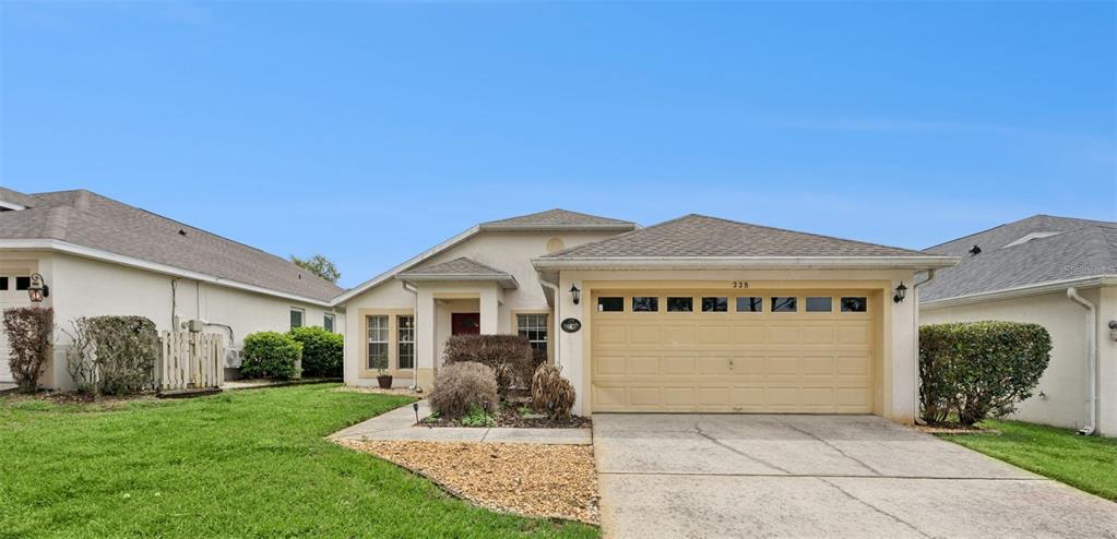 A single-story house features a tan stucco exterior, a two-car garage, and a front lawn — 228 TROON CIRCLE, DAVENPORT, FL