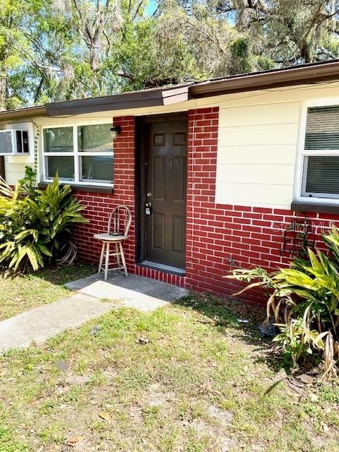 A brick and siding exterior features a front door, a window, and a wooden chair — 9420 GREYSTONE ROAD, THONOTOSASSA, FL
