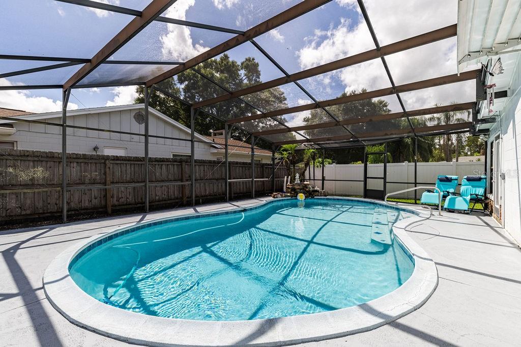 An outdoor swimming pool with a screen enclosure, concrete deck, and a wooden privacy fence — 4268 LAKE ELEANOR DRIVE, MOUNT DORA, FL