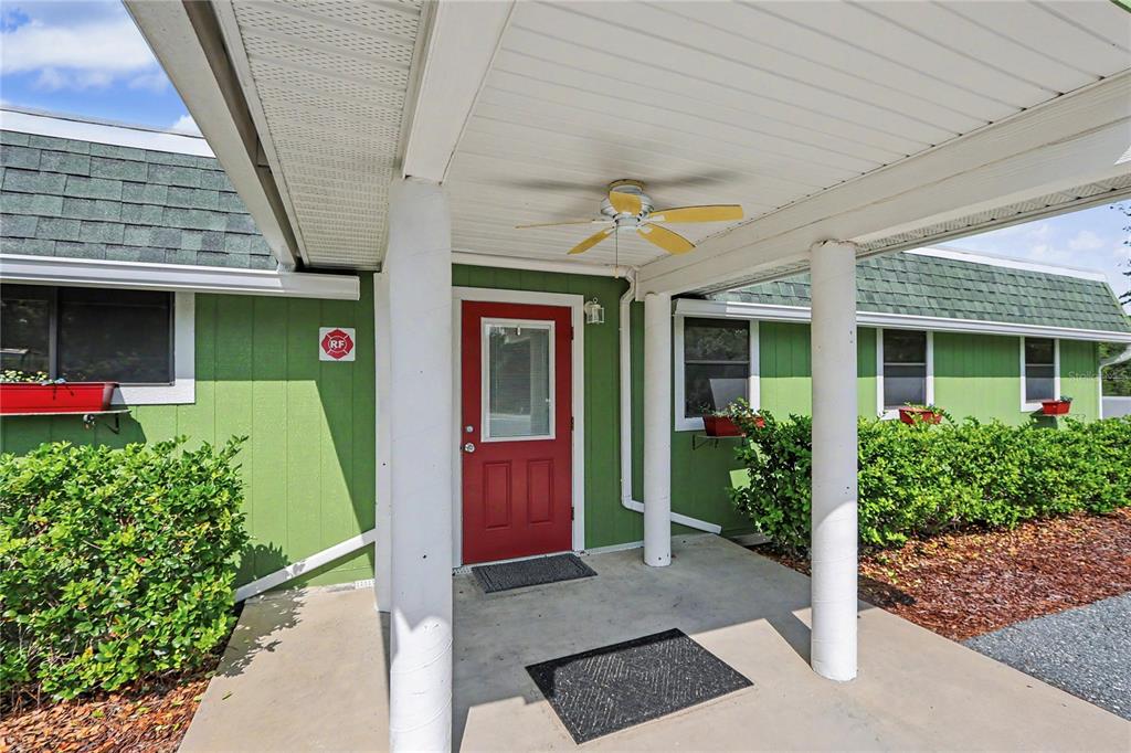 A green house exterior features a red front door under a covered porch with columns — 11840 N ANGUS HILLS TERRACE, DUNNELLON, FL