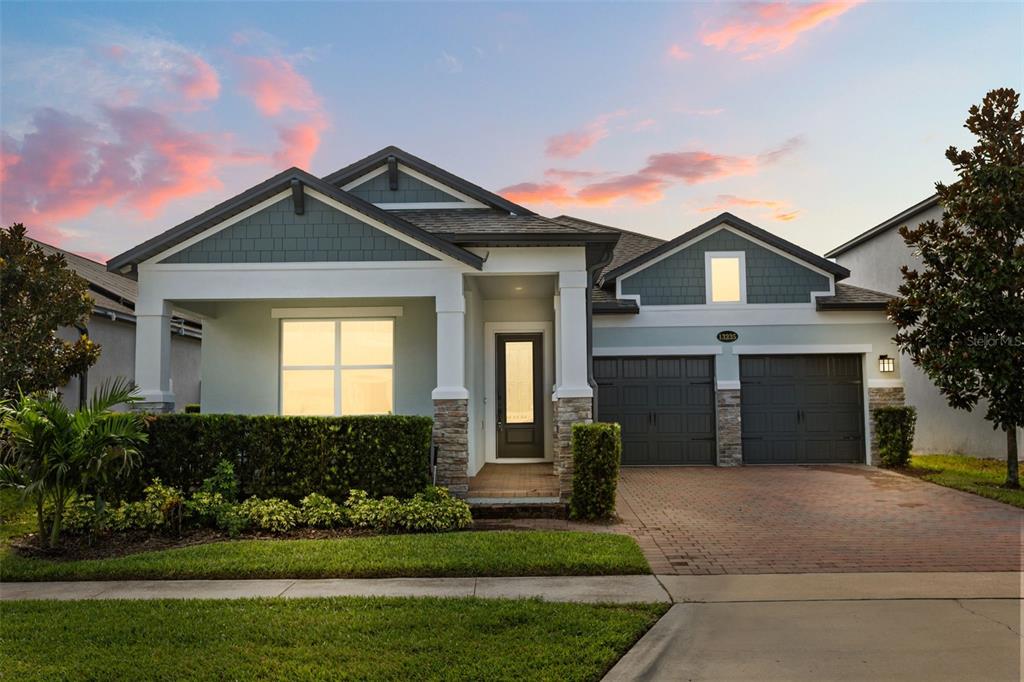A single-story house with a brick driveway, stone accents, and a dark-trimmed front entrance — 13235 SPRING GROVE WAY, WINTER GARDEN, FL
