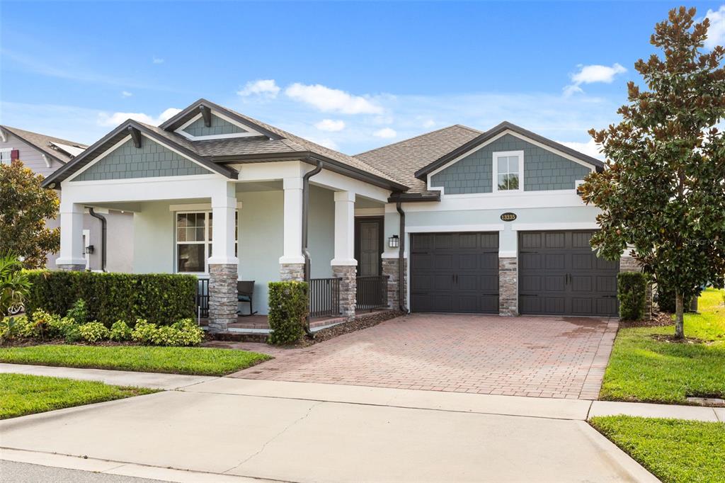 A single-story house with a front porch, stone pillars, and a two-car garage — 13235 SPRING GROVE WAY, WINTER GARDEN, FL