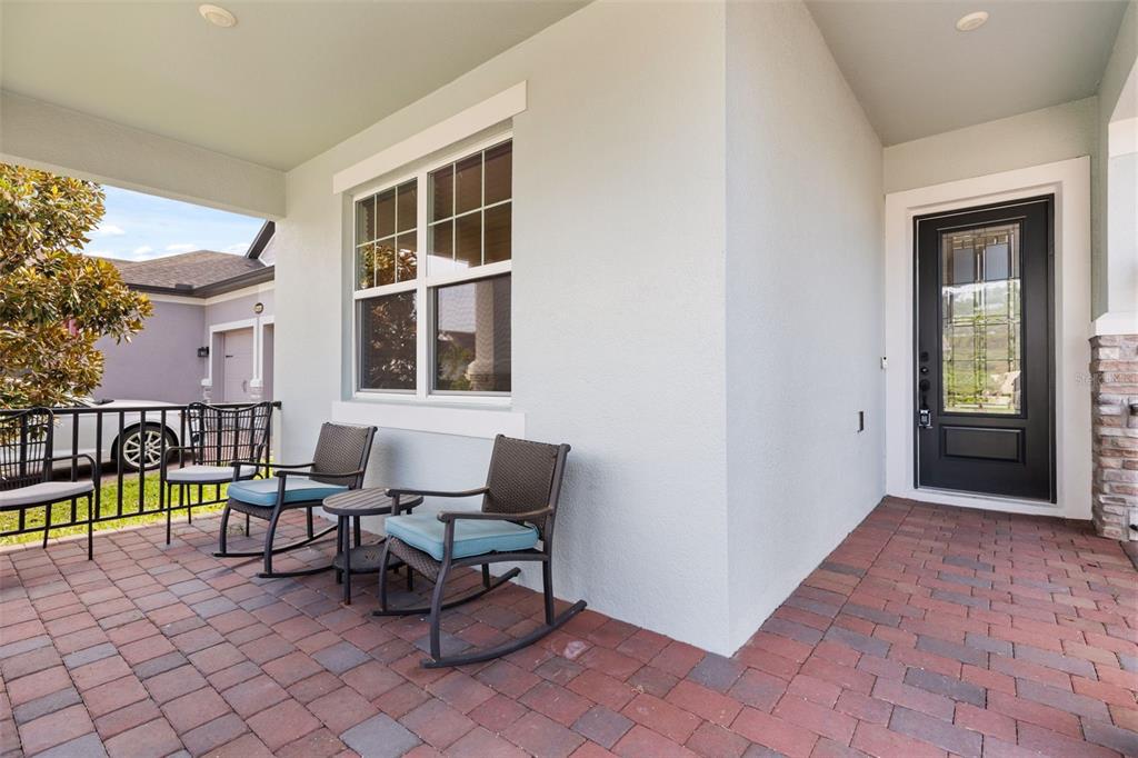 A covered front porch features brick pavers, two rocking chairs, and a black front door — 13235 SPRING GROVE WAY, WINTER GARDEN, FL