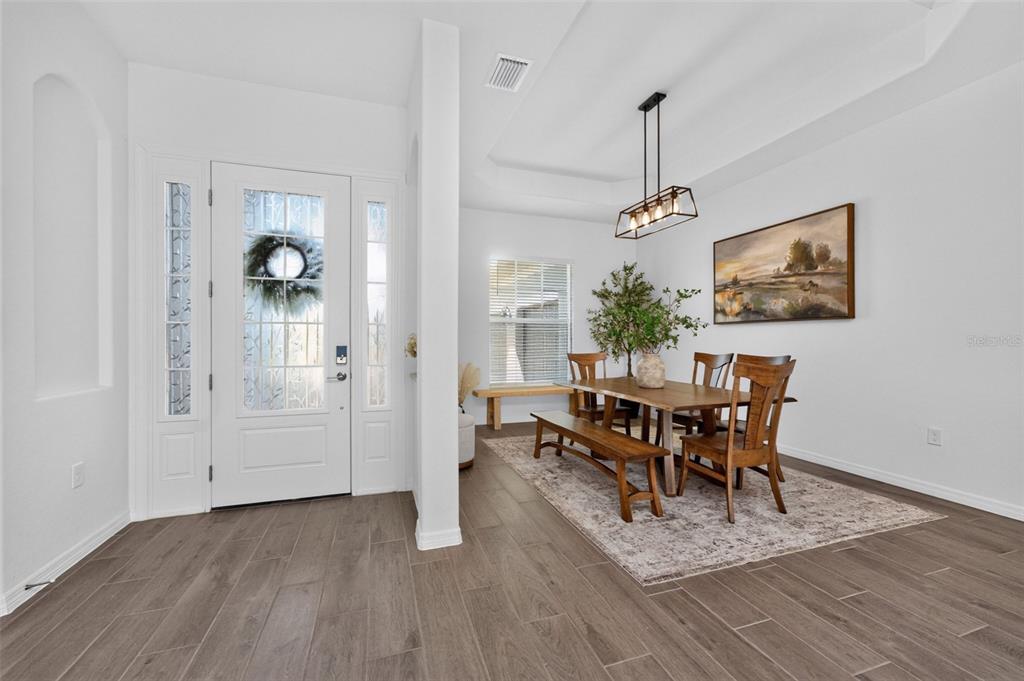 A dining area with wood-look tile floors, a wooden table, and a modern light fixture — 25076 REDWOOD COURT, PUNTA GORDA, FL