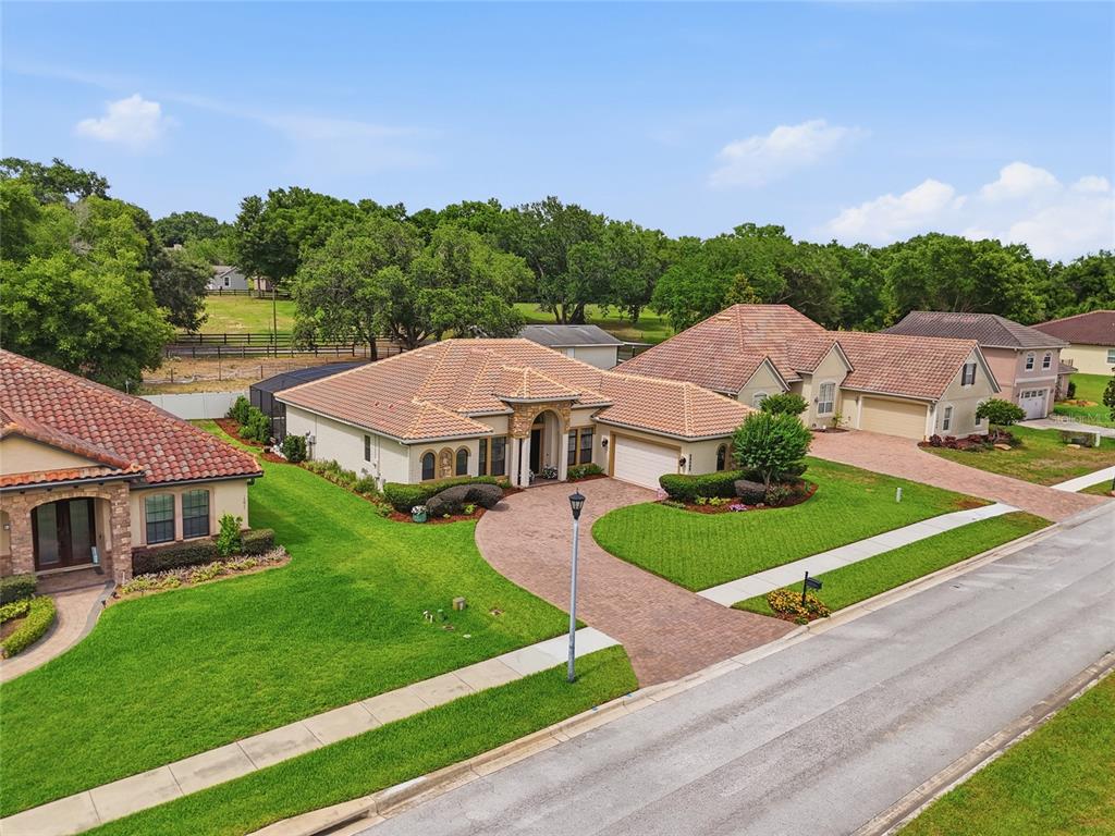 An aerial view shows three suburban houses with tiled roofs, brick driveways, and green lawns — 12825 BRUNELLO CIRCLE, CLERMONT, FL