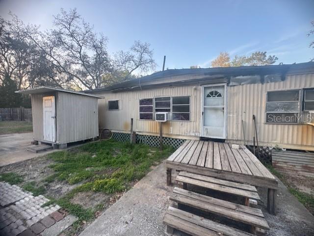 Exterior view of a weathered mobile home with a small shed and wooden deck — 4639 CR 690, WEBSTER, FL