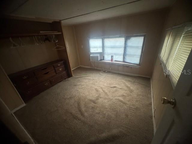 A bedroom with tan carpet, wood-paneled walls, a built-in dresser, and a window air conditioner — 4639 CR 690, WEBSTER, FL