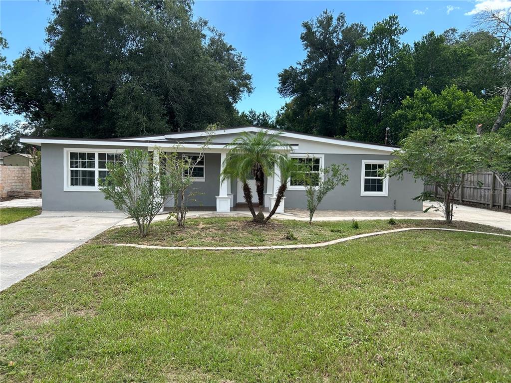 A single-story gray house with a covered porch, white trim, and a front lawn — 104 E GARDENIA DRIVE, ORANGE CITY, FL