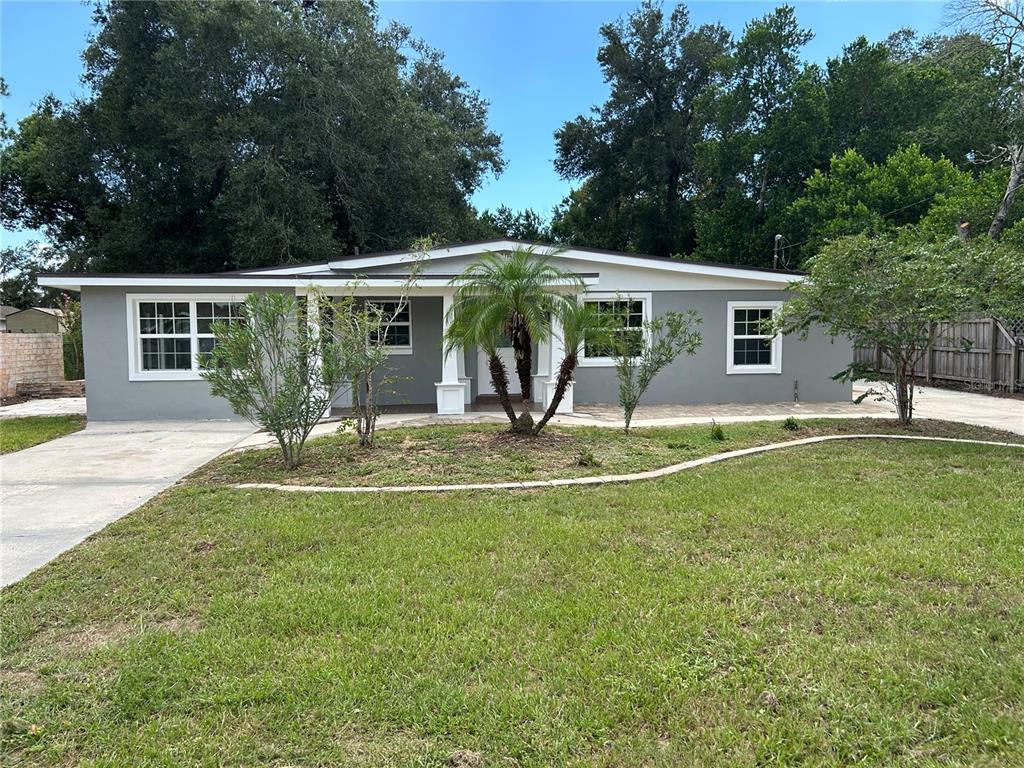 A single-story gray house with a front porch, white trim, and a manicured lawn — 104 E GARDENIA DRIVE, ORANGE CITY, FL