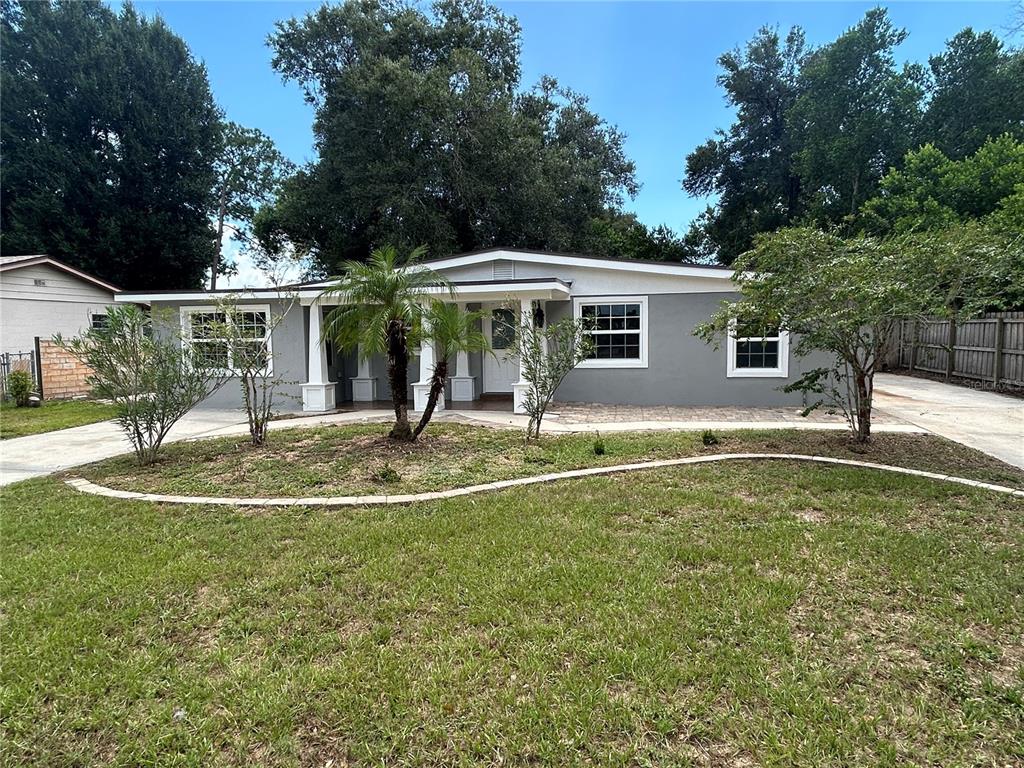 A single-story gray house with a covered front porch and a curved landscape bed — 104 E GARDENIA DRIVE, ORANGE CITY, FL