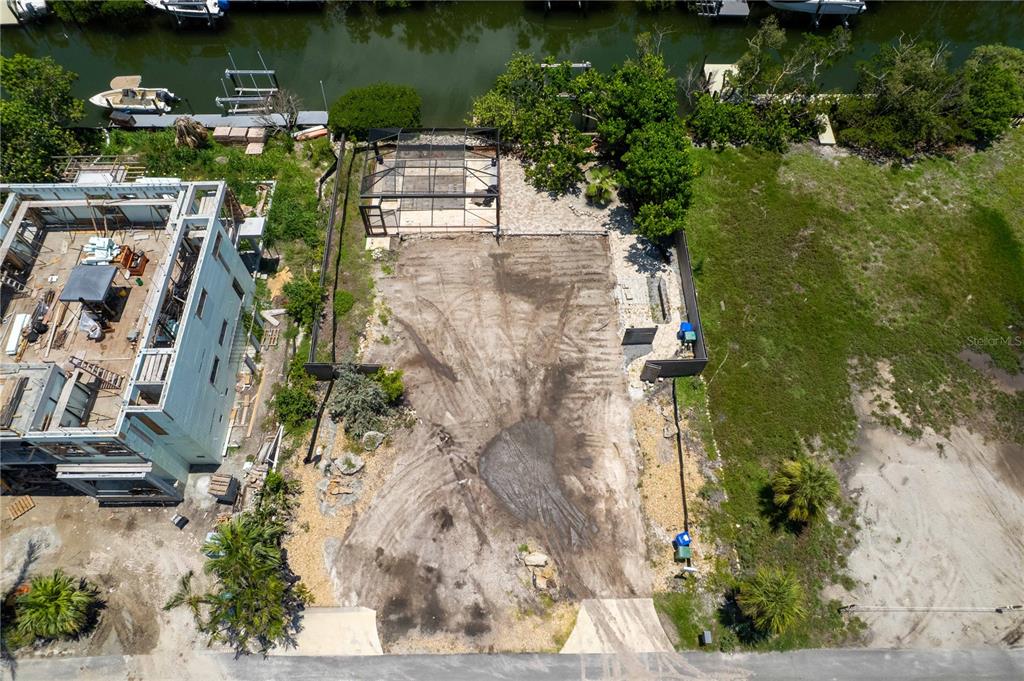 An aerial view shows a waterfront lot with a cleared sandy area and a screened enclosure — 640 LYONS LANE, LONGBOAT KEY, FL