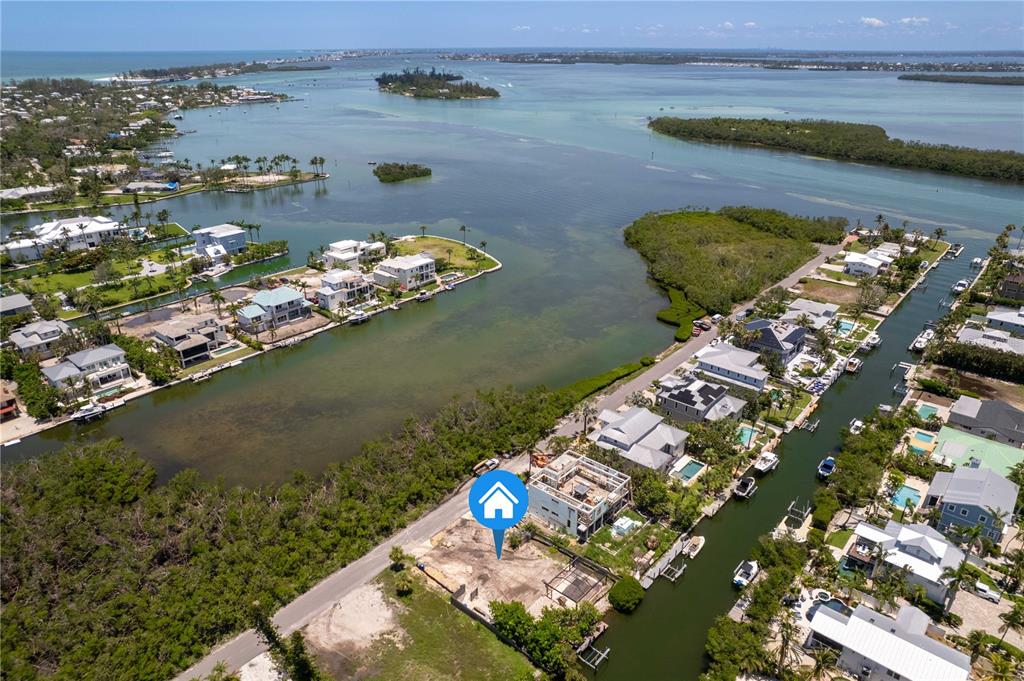 An aerial view shows a vacant waterfront lot under construction near a canal and bay — 640 LYONS LANE, LONGBOAT KEY, FL