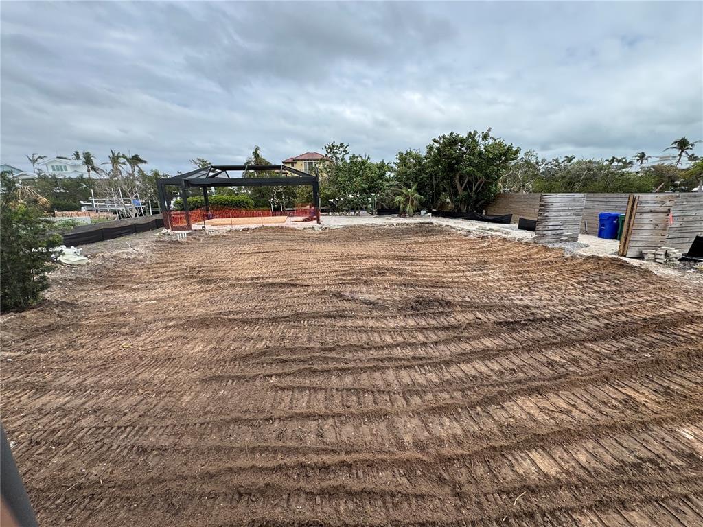 A large, cleared dirt lot features tire tracks and a black metal gazebo structure — 640 LYONS LANE, LONGBOAT KEY, FL