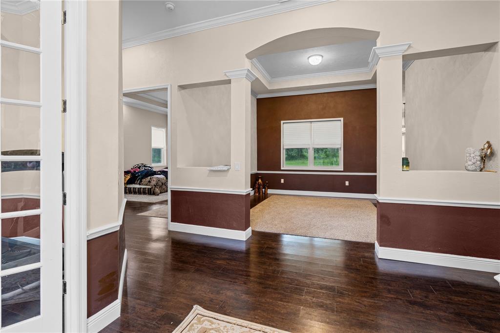 A room with dark wood floors, a carpeted area, and brown accent walls with white trim — 16635 SW 139TH AVENUE, ARCHER, FL