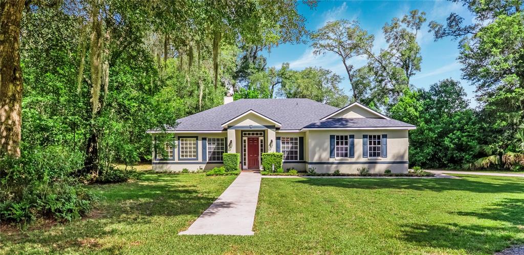 A red front door with sidelights and a transom window sits on a brick porch — 1085 TAYLOR ROAD E, DELAND, FL